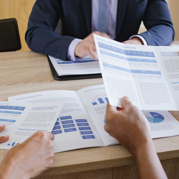 Couple looking leaflet while discussing with banker at home.